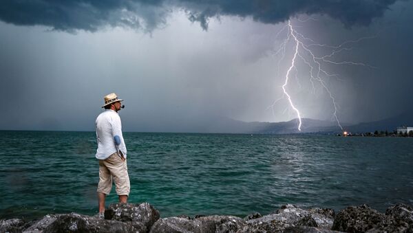 Homem e relâmpago ao fundo no lago de Genebra, na Suíça - Sputnik Brasil
