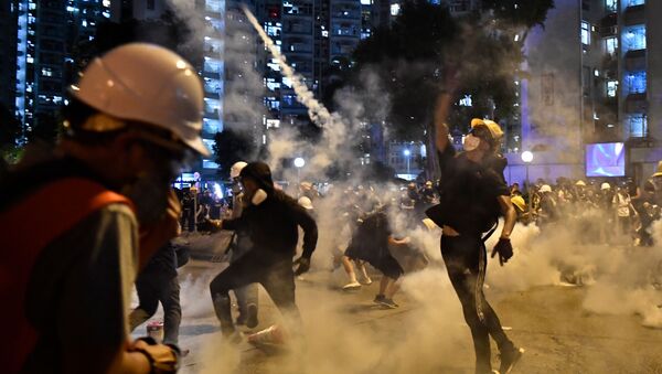 Manifestantesjogam de volta contra a polícia gás lacrimogênico durante protestsos em Hong Kong - Sputnik Brasil