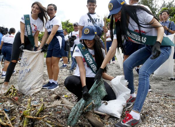 A hondurenha Rita Velásquez, à direita, e a sul-africana Nazia Wadee, no centro, participam de ato em conjunto com a Marinha das Filipinas para recolher lixo de praia e alertar o público para a proteção da natureza, nesta segunda feira (30).  - Sputnik Brasil