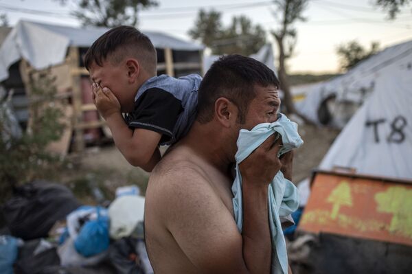 Homem com criança durante confrontos perto do campo de refugiados de Moria, na ilha grega de Lesbos - Sputnik Brasil