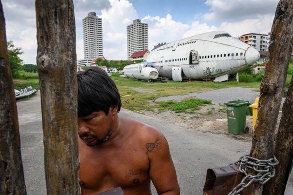 Homem cobrando entrada no portão em frente a aviões abandonados no local turístico chamado de cemitério dos aviões, nos subúrbios de Bankok - Sputnik Brasil