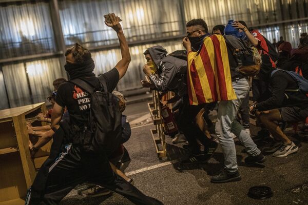 Um manifestante pró-independência atira uma pedra à polícia, que não se vê na fotografia, durante uma manifestação no aeroporto de El Prat - Sputnik Brasil