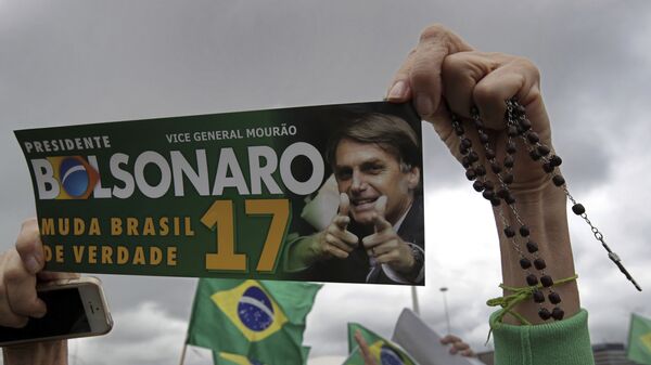 Apoiadora do então candidato à Presidência da República do Brasil, Jair Bolsonaro (PSL), segura terço e uma foto do candidato, Brasília, 21 de outubro de 2018 - Sputnik Brasil