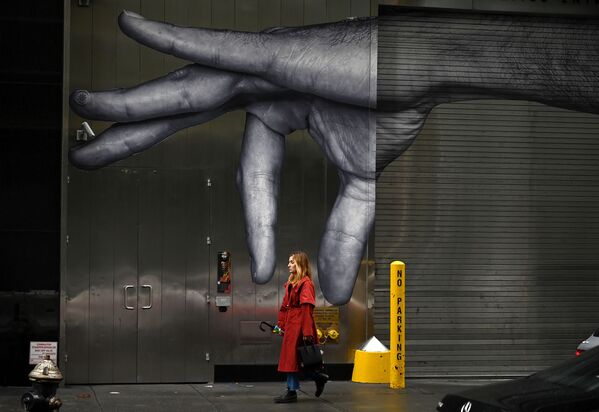 Mulher caminha em rua de Nova York, em ângulo que combina com a foto de fundo - Sputnik Brasil