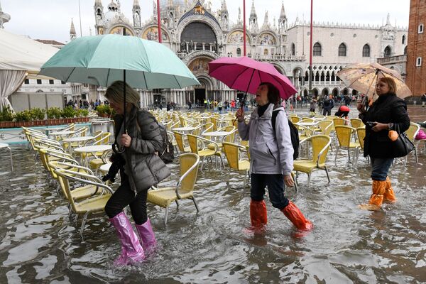 Turistas com botas de plástico andando pela Praça de San Marco inundada - Sputnik Brasil