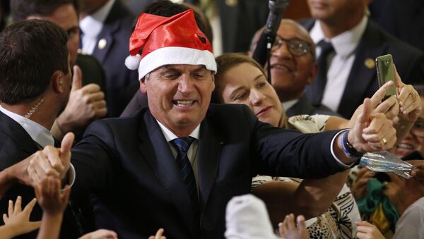 Presidente Jair Bolsonaro usando chapéu de Papai Noel durante a celebração do Natal com os funcionários e estudantes no Palácio do Planalto, em Brasília - Sputnik Brasil