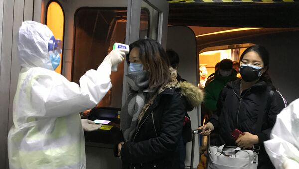Agentes de saúde checam a temperatura de passageiros que chegam da cidade chinesa de Wuhan no aeroporto de Pequim no dia 22 de janeiro de 2020. - Sputnik Brasil