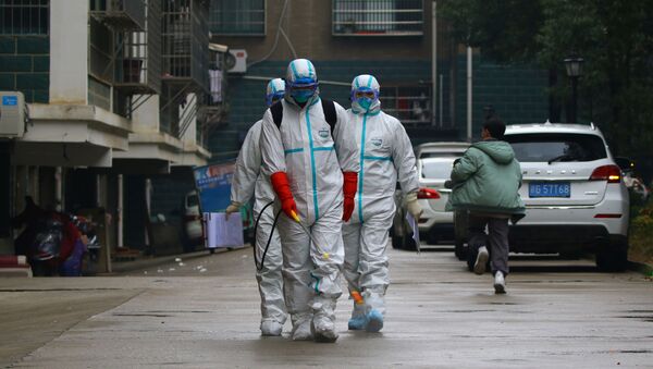 Trabalhadores do departamento local de controle e prevenção de doenças desinfectam área residencial após surto de coronavírus na província de Jiangxi, China, 25 de janeiro de 2020 - Sputnik Brasil