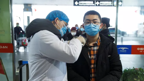 Agente de saúde medindo a temperatura de passageiro na China - Sputnik Brasil