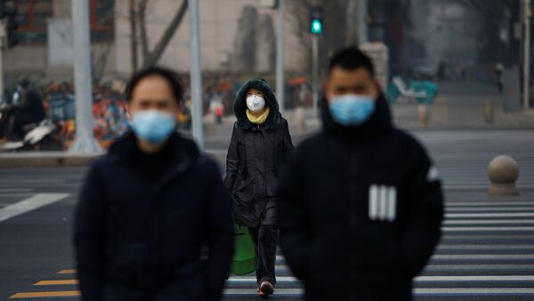 Pessoas usando máscaras atravessam uma rua na China enquanto o país é atingido por um surto do novo coronavírus, em Pequim, 28 de janeiro de 2020 - Sputnik Brasil