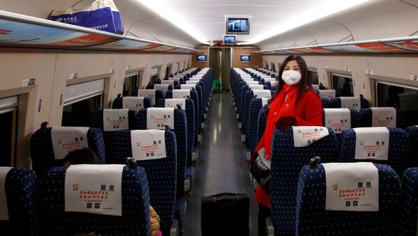 Uma mulher usa uma máscara enquanto viaja em um trem de alta velocidade perto de Jiujiang, na província de Jianxi, em meio ao surto de coronavírus na China. - Sputnik Brasil