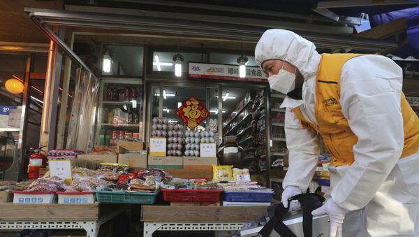 Para deter propagação do coronavírus, homem aplica desinfetante em mercado na China - Sputnik Brasil