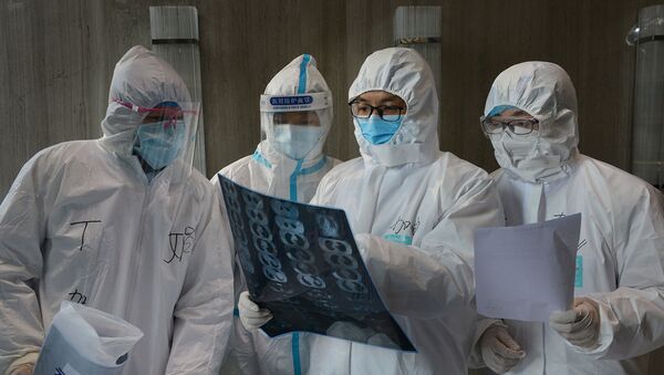 Médicos em trajes de proteção inspecionam imagem de tomografia computadorizada em hospital no município chinês de Yunmeng, em Hubei, a província mais atingida pelo novo surto de coronavírus, em 20 de fevereiro de 2020 - Sputnik Brasil