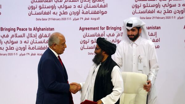 Representante dos EUA para o Afeganistão, Zalmay Khalizad (à esquerda) aperta mão do representante do Talibã (Abdul Ghani Baradar) em ato de assinatura de acordo de paz entre ambos os lados em 29 de fevereiro no Qatar - Sputnik Brasil