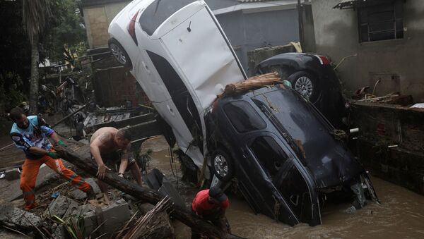 Moradores tentam remover carros danificados de um rio que transbordou no bairro de Realengo, no Rio de Janeiro, após fortes chuvas - Sputnik Brasil