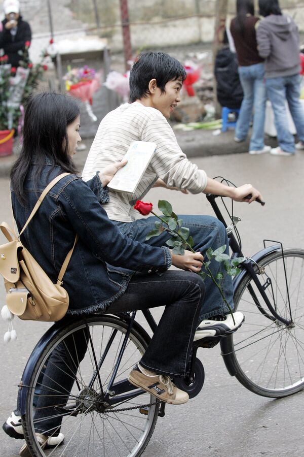 Menina com uma rosa em uma rua de Hanói em bicicleta, Vietnã, 8 de março de 2006. No Vietnã a festa se tornou o equivalente do Dia dos Namorados - Sputnik Brasil