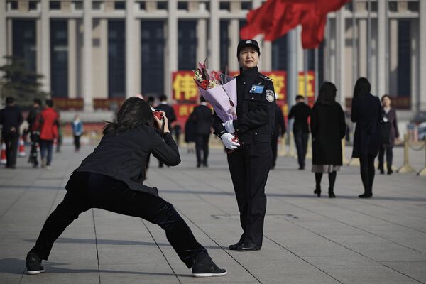 Mulher tirando foto de uma policial com flores na Praça da Paz Celestial, Pequim, China, em 8 de março de 2019 - Sputnik Brasil
