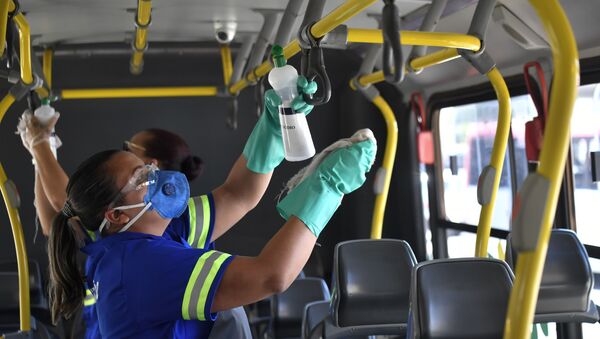 Mulher utiliza máscara de proteção facial como prevenção ao contágio do novo coronavírus (Covid-19) e realiza higienização em um ônibus na Rodoviária Central de Brasília (DF), nesta quarta-feira (18).  - Sputnik Brasil
