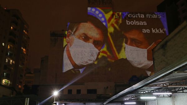 Paulistano projeta imagem do presidente Jair Bolsonaro e de seu ministro da Saúde, Luiz Mandetta, em fachada de prédio durante novo panelaço, em São Paulo, 19 de março de 2020   - Sputnik Brasil
