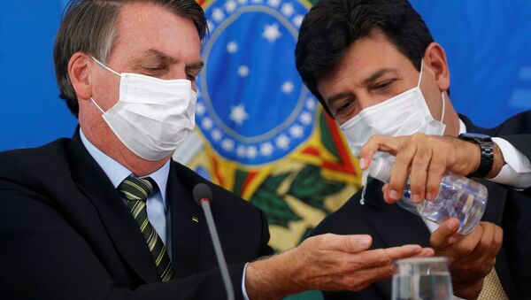Presidente brasileiro, Jair Bolsonaro, em conferência junto com seu ministro da Saúde, Luiz Henrique Mandetta, passa álcool-gel na mão e usa máscara - Sputnik Brasil