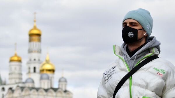 Jovem usando máscara protetora próximo a igreja ortodoxa em Moscou, 21 de março de 2020      - Sputnik Brasil