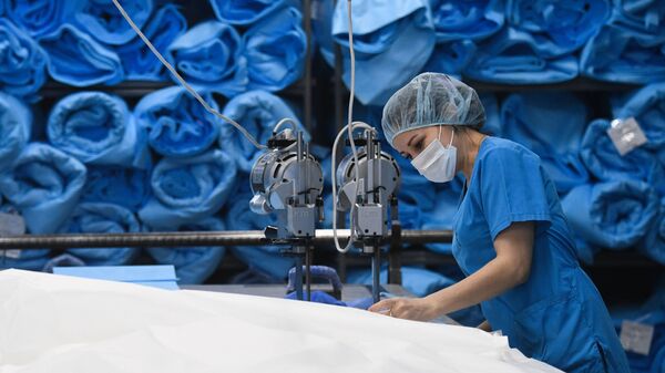 Funcionária de fábrica produz roupas médicas e máscaras de proteção na região de Novossibirsk, na Rússia, 20 de março de 2020  - Sputnik Brasil