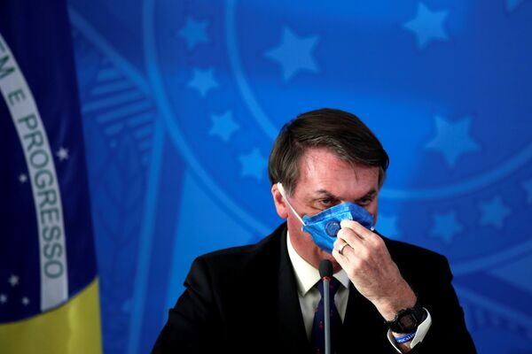 Presidente brasileiro Jair Bolsonaro ajusta sua máscara protetora facial em comunicado à imprensa durante a pandemia de coronavírus, em Brasília, Brasil, 20 de março de 2020 - Sputnik Brasil