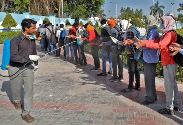 Funcionário municipal borrifa desinfetante em trabalhadores migrantes na cidade indiana de Lucknow - Sputnik Brasil