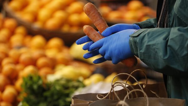 Consumidor usa luvas para selecionar cenouras em mercado em Londres, no Reino Unido, 3 de abril de 2020 - Sputnik Brasil