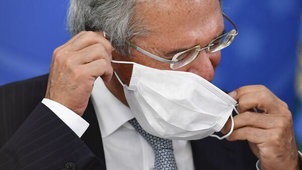 O ministro da economia, Paulo Guedes, coloca uma máscara para se proteger da COVID-19 durante coletiva de imprensa em Brasília. - Sputnik Brasil