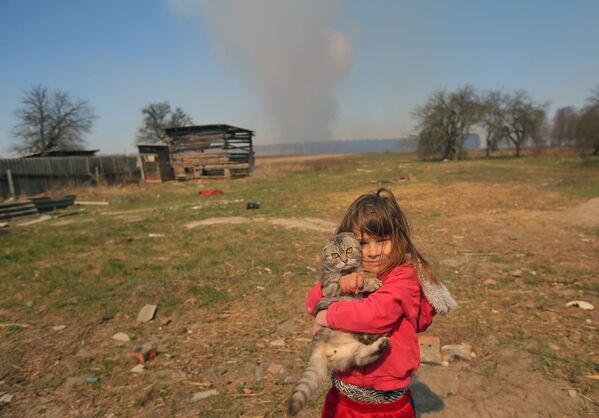 Garota com gato em pátio de casa no vilarejo de Ragovka, em meio ao incêndio na zona de exclusão da usina nuclear de Chernobyl - Sputnik Brasil