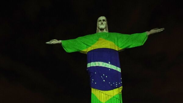 Estátua do Cristo Redentor do Rio de Janeiro é iluminada com a bandeira do Brasil, durante a pandemia do novo coronavírus, no Rio de Janeiro, 12 de abril de 2020 - Sputnik Brasil