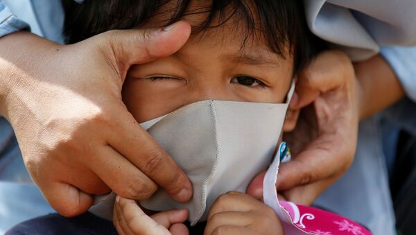 Pessoa ajusta máscara em criança na capital da Indonésia, Jacarta, em meio à pandemia de COVID-19, 23 de abril de 2020 - Sputnik Brasil