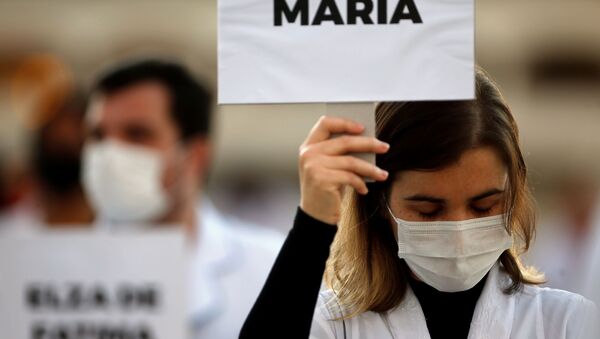 Enfermeira empunha cartaz com nome de colega vítima da COVID-19, durante protesto em Brasília, 12 de maio de 2020 - Sputnik Brasil