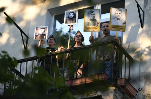 Pessoas em casa cantando canções na varanda com retratos de seus parentes que participaram na Grande Guerra pela Pátria, em Sevastopol, Crimeia, Rússia - Sputnik Brasil
