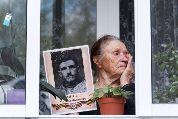 Moradora da cidade de Irkutsk na varanda com retrato de seu parente veterano da Grande Guerra pela Pátria - Sputnik Brasil