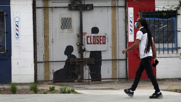 Um pedestre caminha de máscara durante a pandemia da COVID-19 em frente a uma barbearia fechada em Washington, nos EUA, em 8 de maio de 2020. - Sputnik Brasil