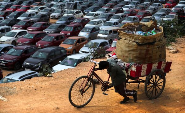 Homem empurra sua bicicleta carregando uma grande quantidade de matérias recicláveis em Bengaluru, na Índia - Sputnik Brasil