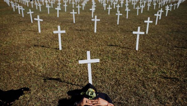 Ativista ao lado de cruzes, simbolizando os que morreram por coronavírus, em frente ao Congresso Nacional durante protesto contra presidente do Brasil, Jair Bolsonaro, em Brasília, Brasil, 28 de junho de 2020 - Sputnik Brasil
