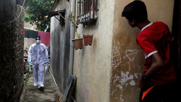 Profissional da saúde com traje de proteção individual passa por favela em Mumbai, Índia - Sputnik Brasil