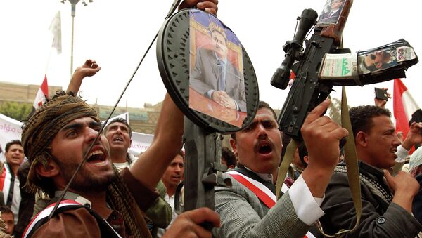 Manifestantes iemenitas seguram rifles com fotos do ex-presidente do país Ali Abdullah Saleh durante um ato contra os ataques aéreos realizados pela coalizão liderada pela Arábia Saudita contra os houthis na capital Sanaa em 3 de abril de 2015 - Sputnik Brasil