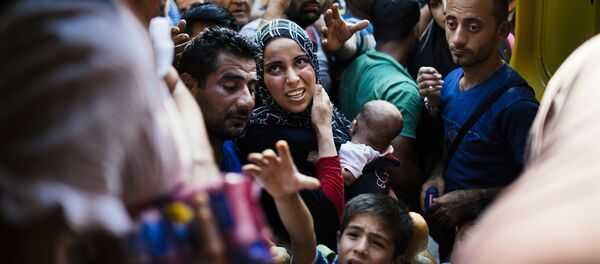 Migrantes ficam à espera de comida distribuída por voluntários macedônios na estação ferroviária em Gevgelija, na fronteira entre Macedônia e Grécia. 4 de agosto de 2015 - Sputnik Brasil