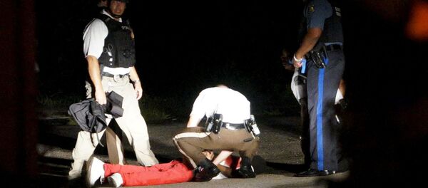 Um manifestante ensanguentado é socorrido por um policial em Fergusson. - Sputnik Brasil