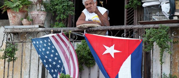 Cubano acena positivamente de sua varanda decorada com as bandeiras dos EUA e de Cuba - Sputnik Brasil