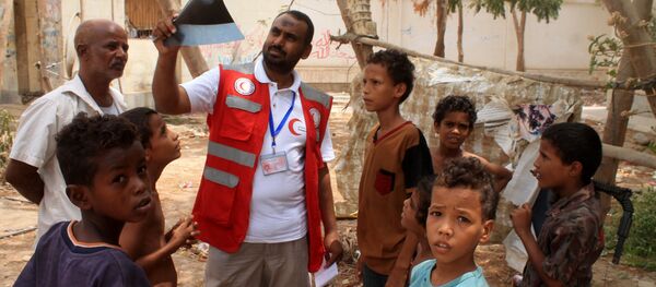 Um representante da Cruz Vermelha com um grupo de crianças iemenitas evacuadas na cidade portuária de Aden, no sul do país - Sputnik Brasil