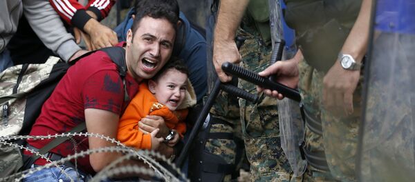 Imigrante com criança durante conflito entre imigrantes e polícia da Macedônia - Sputnik Brasil