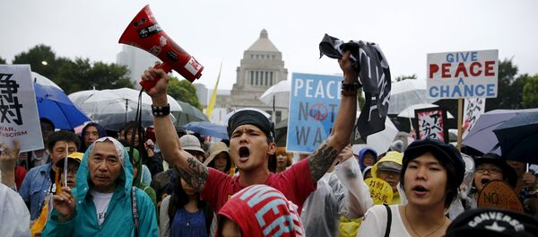 Manifestantes empunham cartazes com slogans contra o primeiro ministro do país, Shinzo Abe e sua política de segurança, do lado de fora do Parlamento japonês em Tóquio - Sputnik Brasil
