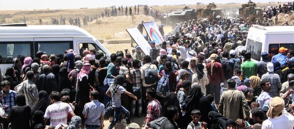 Refugiados sírios à espera de transporte após atravessar a fronteira com a Turquia da cidade síria Tal Abyad - Sputnik Brasil