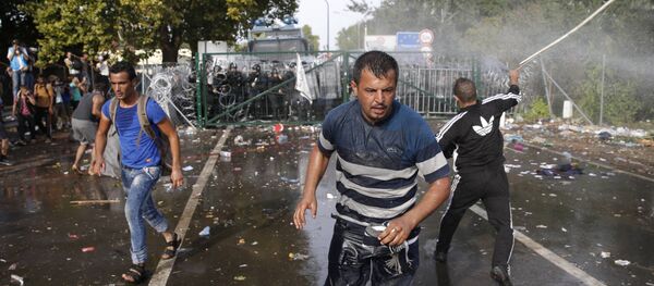 Impedidos de entrar na Hungria, refugiados atiram objetos contra a polícia húngara, que responde com gás de pimenta e canhões de água - Sputnik Brasil