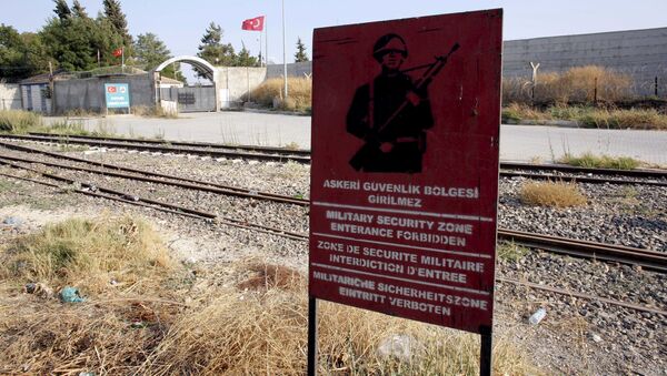 A Turkish military warning sign, with the closed Karkamis border gate in the background, is pictured in Karkamis, bordering with the Islamic State-held Syrian town of Jarablus, in Gaziantep province, Turkey - Sputnik Brasil
